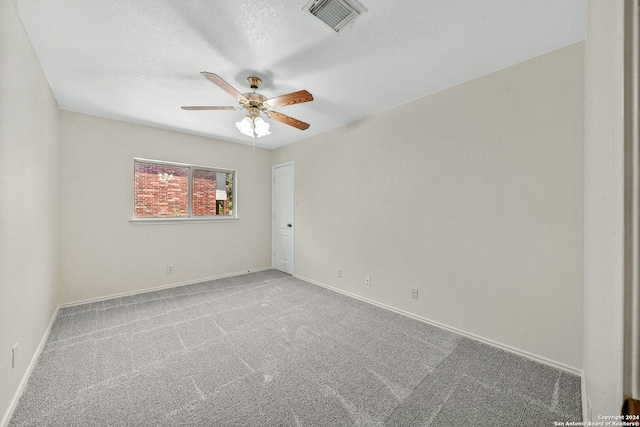 carpeted spare room with baseboards, a textured ceiling, visible vents, and a ceiling fan