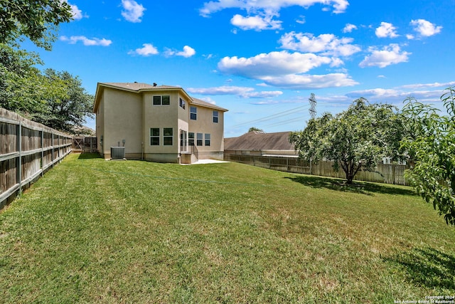 rear view of property with a lawn, cooling unit, a fenced backyard, and stucco siding