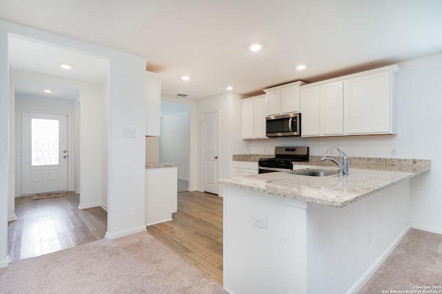 kitchen with stainless steel appliances, sink, kitchen peninsula, light hardwood / wood-style floors, and white cabinetry