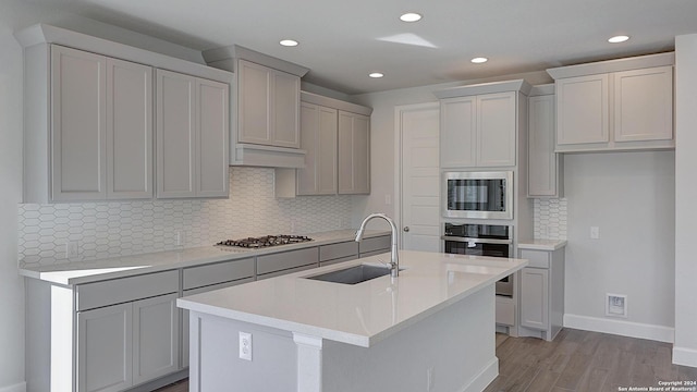 kitchen featuring stainless steel appliances, a kitchen island with sink, light hardwood / wood-style flooring, and sink