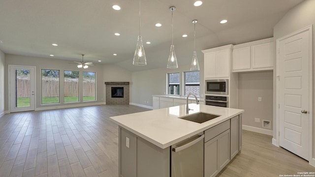 kitchen featuring an island with sink, white cabinets, appliances with stainless steel finishes, ceiling fan, and sink