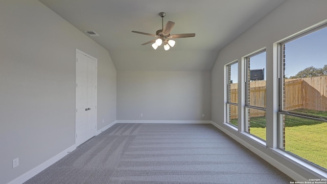 carpeted spare room with a wealth of natural light, ceiling fan, and lofted ceiling