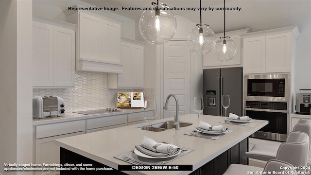 kitchen with stainless steel appliances, sink, decorative light fixtures, white cabinetry, and decorative backsplash