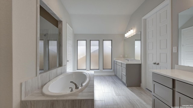 bathroom featuring independent shower and bath, lofted ceiling, and vanity