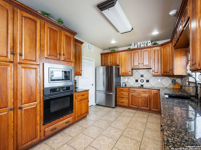 kitchen with sink, dark stone countertops, tasteful backsplash, and stainless steel appliances