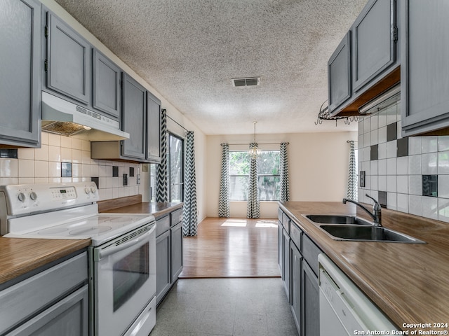 kitchen featuring tasteful backsplash, white appliances, a textured ceiling, light hardwood / wood-style floors, and sink