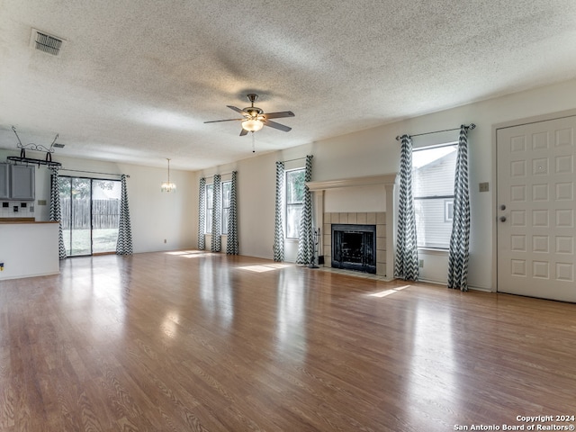 unfurnished living room with plenty of natural light, a fireplace, ceiling fan, and hardwood / wood-style floors