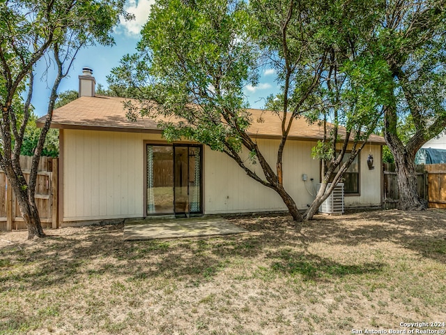 rear view of house with cooling unit and a yard