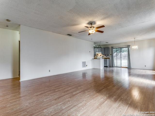 unfurnished living room featuring light hardwood / wood-style floors, a textured ceiling, and ceiling fan with notable chandelier