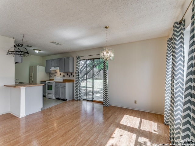 unfurnished living room featuring an inviting chandelier, a textured ceiling, and light wood-type flooring