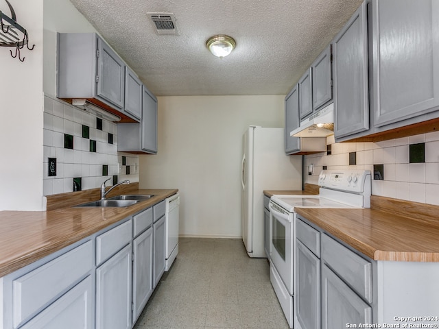 kitchen featuring white appliances, light tile patterned floors, a textured ceiling, gray cabinets, and decorative backsplash