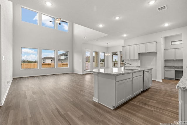 kitchen featuring sink, a center island with sink, decorative backsplash, and dark hardwood / wood-style floors