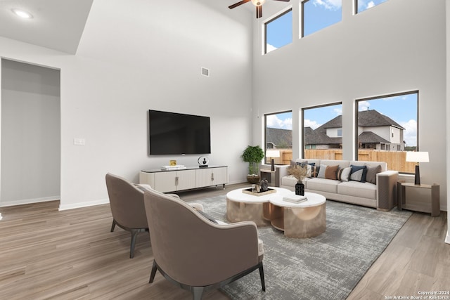 living room featuring ceiling fan, a towering ceiling, and hardwood / wood-style flooring