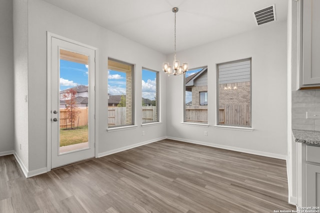 unfurnished dining area with light wood-type flooring and a notable chandelier