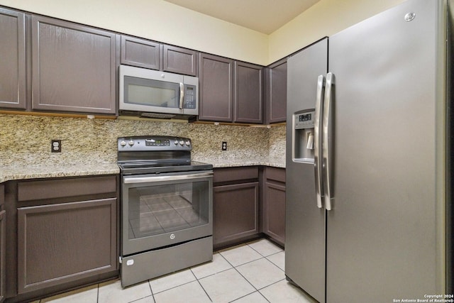 kitchen featuring stainless steel appliances, tasteful backsplash, light tile patterned flooring, and dark brown cabinetry