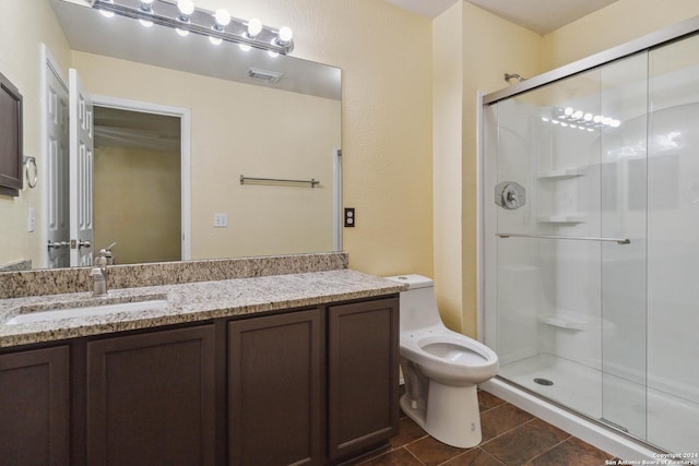 bathroom with vanity, toilet, tile patterned flooring, and a shower with door