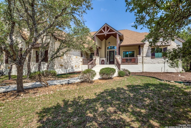 view of front facade featuring french doors, roof with shingles, stucco siding, a front yard, and stone siding