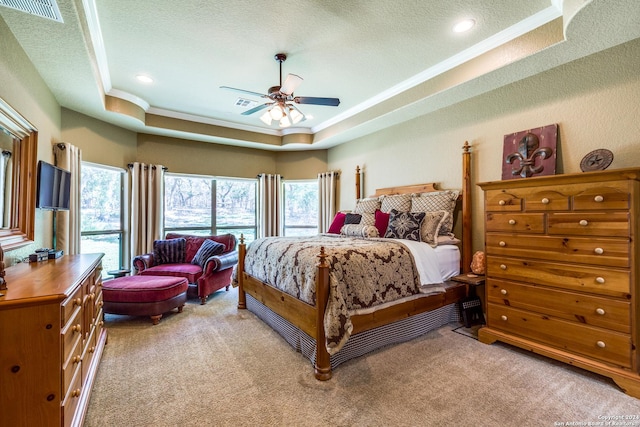 bedroom with ornamental molding, a raised ceiling, light colored carpet, and visible vents