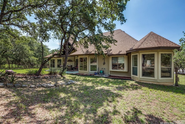 back of property featuring a patio area, roof with shingles, and a yard