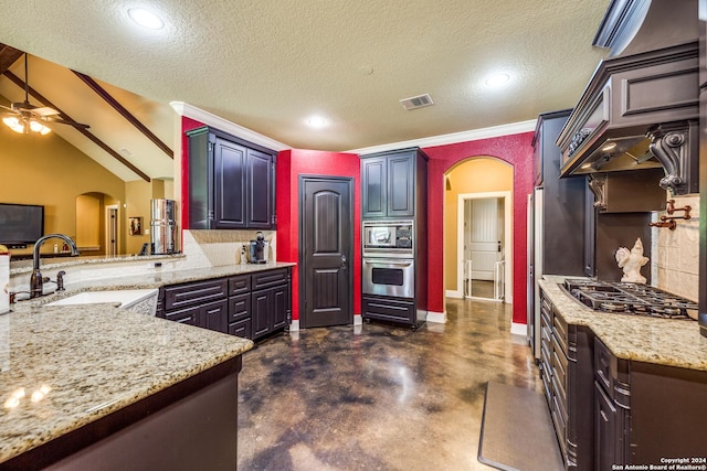 kitchen featuring arched walkways, light stone counters, a sink, visible vents, and appliances with stainless steel finishes