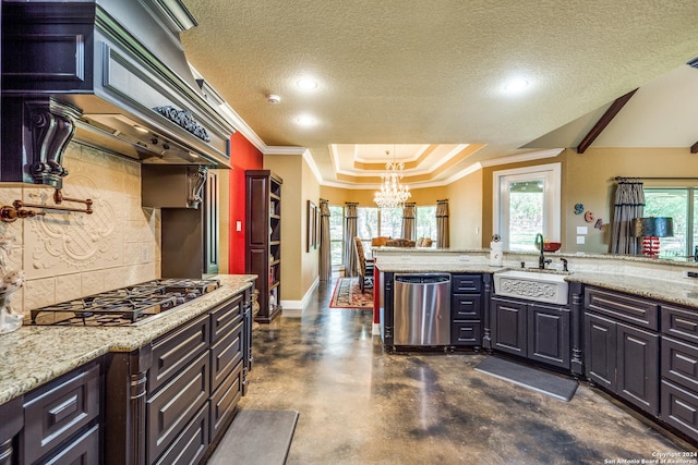 kitchen with a raised ceiling, custom range hood, appliances with stainless steel finishes, an inviting chandelier, and a sink