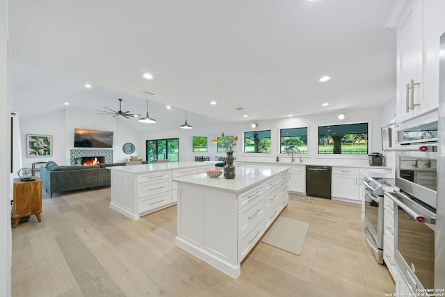 kitchen with a fireplace, dishwasher, white cabinetry, a kitchen island, and lofted ceiling