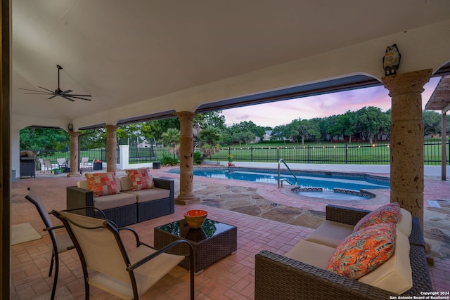 patio terrace at dusk featuring ceiling fan, a swimming pool with hot tub, an outdoor hangout area, and a grill