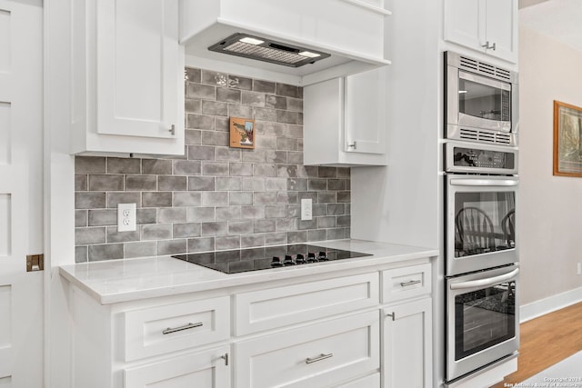 kitchen featuring stainless steel appliances, tasteful backsplash, wood finished floors, and white cabinets