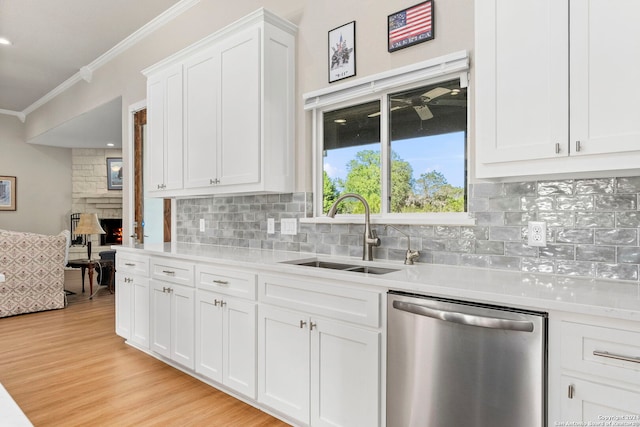 kitchen with crown molding, light countertops, stainless steel dishwasher, white cabinetry, and a sink