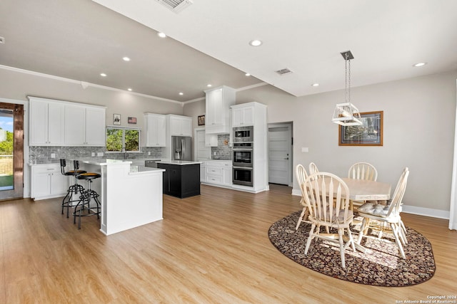 kitchen with stainless steel appliances, light countertops, a kitchen island, and white cabinetry