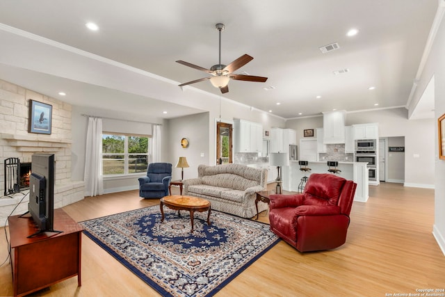 living area with light wood-style flooring, a fireplace, visible vents, baseboards, and crown molding