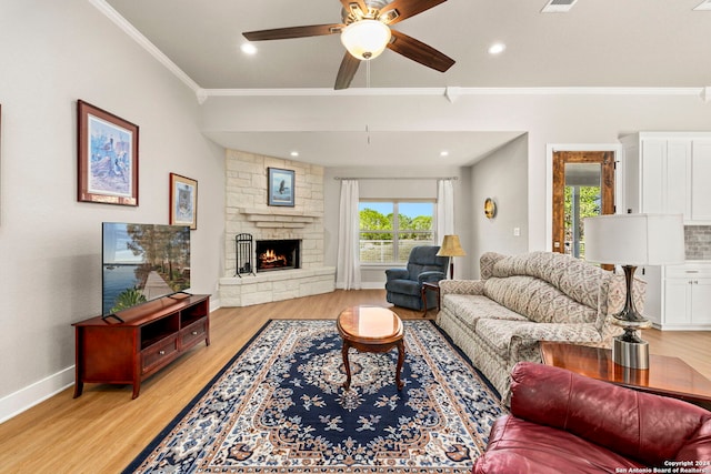 living area with baseboards, light wood-style flooring, ceiling fan, ornamental molding, and a fireplace