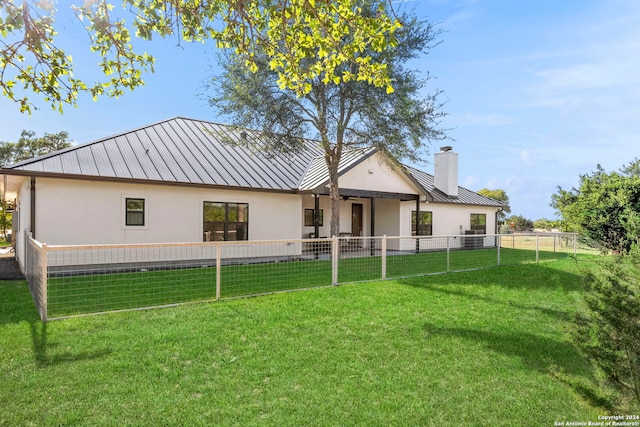 rear view of property featuring metal roof, a yard, and a standing seam roof