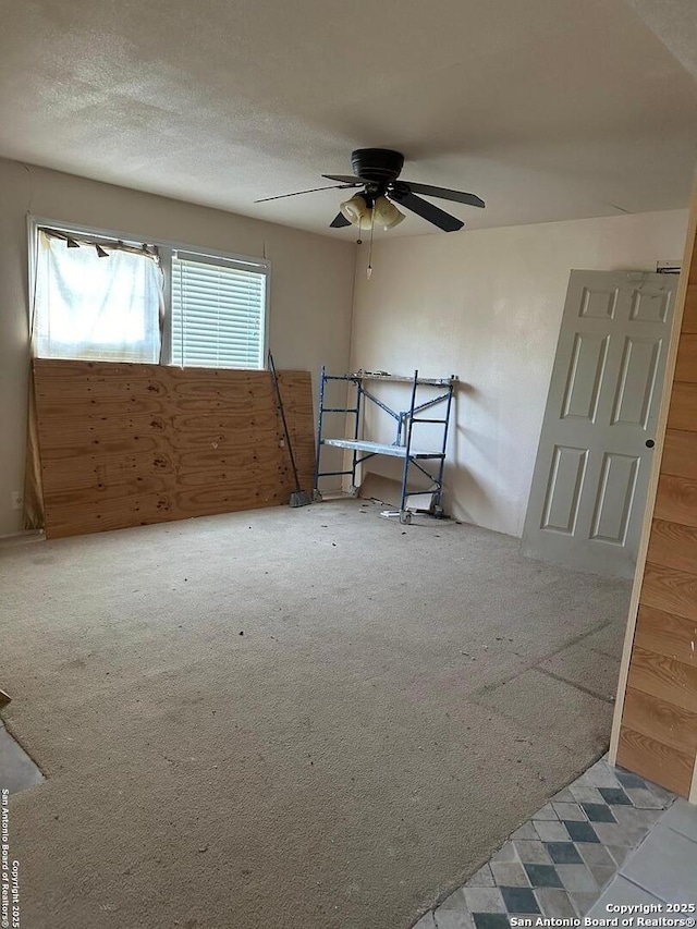 empty room featuring light carpet, ceiling fan, and a textured ceiling