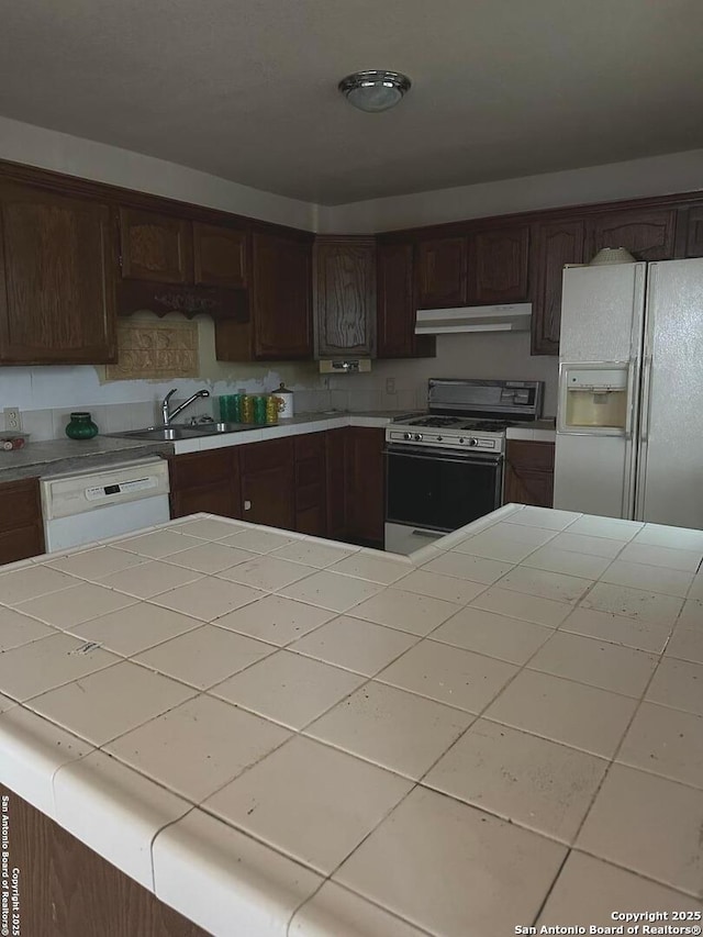 kitchen with tile countertops, sink, dark brown cabinetry, and white appliances