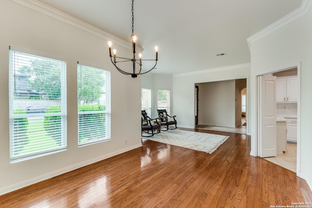 unfurnished dining area featuring an inviting chandelier, crown molding, and light hardwood / wood-style floors