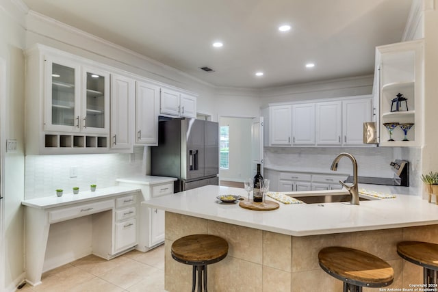 kitchen with sink, a breakfast bar area, white cabinets, range, and stainless steel refrigerator with ice dispenser