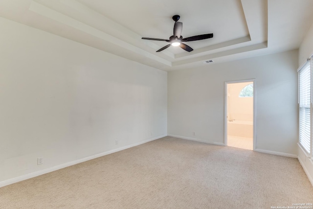 carpeted empty room featuring ceiling fan and a raised ceiling