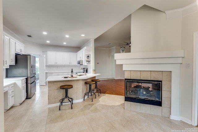 kitchen with crown molding, a breakfast bar, sink, and white cabinets