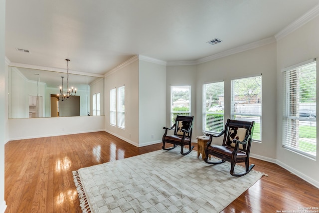 sitting room with hardwood / wood-style flooring, crown molding, a wealth of natural light, and a chandelier