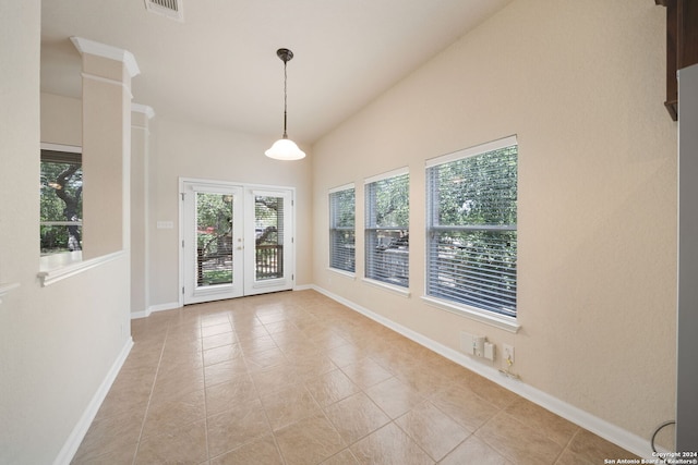 tiled empty room with ornate columns, french doors, and vaulted ceiling