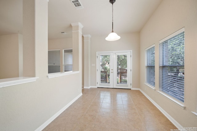 unfurnished dining area featuring ornate columns, french doors, and light tile patterned flooring