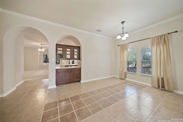 spare room featuring crown molding and ceiling fan with notable chandelier