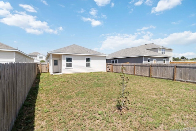 back of property featuring a fenced backyard and a yard