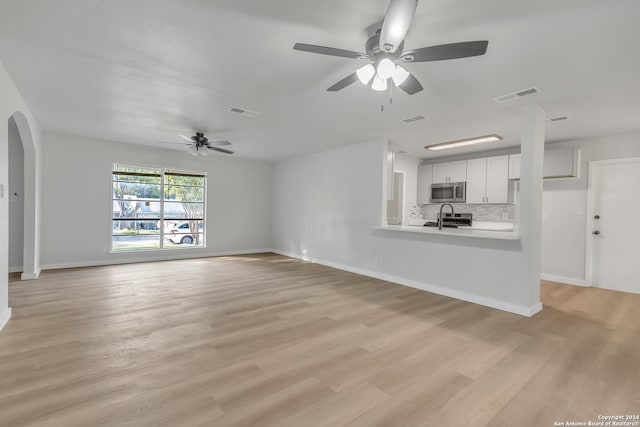 unfurnished living room featuring sink, light hardwood / wood-style flooring, and ceiling fan