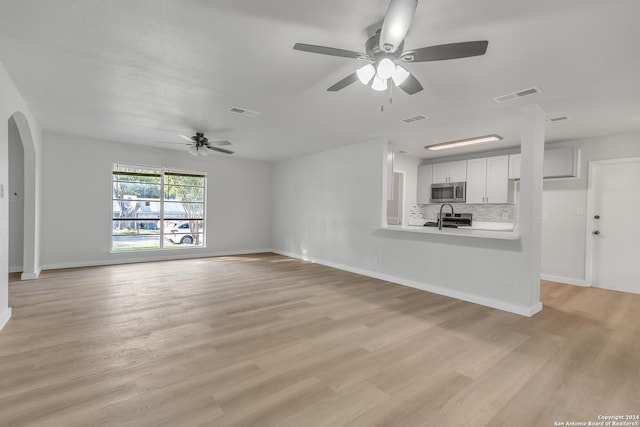 unfurnished living room featuring ceiling fan, sink, and light wood-type flooring