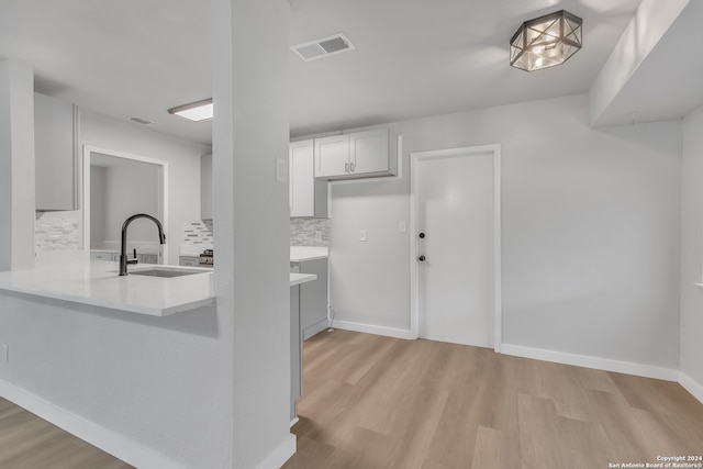 kitchen with light hardwood / wood-style floors, sink, white cabinetry, and tasteful backsplash