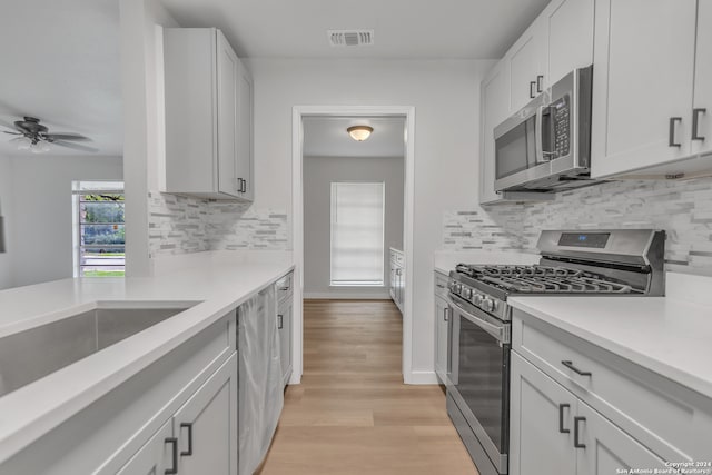 kitchen with white cabinetry, tasteful backsplash, ceiling fan, stainless steel appliances, and light hardwood / wood-style floors