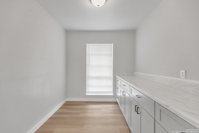 interior space featuring light stone counters, light hardwood / wood-style flooring, and white cabinets