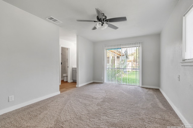 unfurnished bedroom featuring light carpet, ensuite bath, and ceiling fan